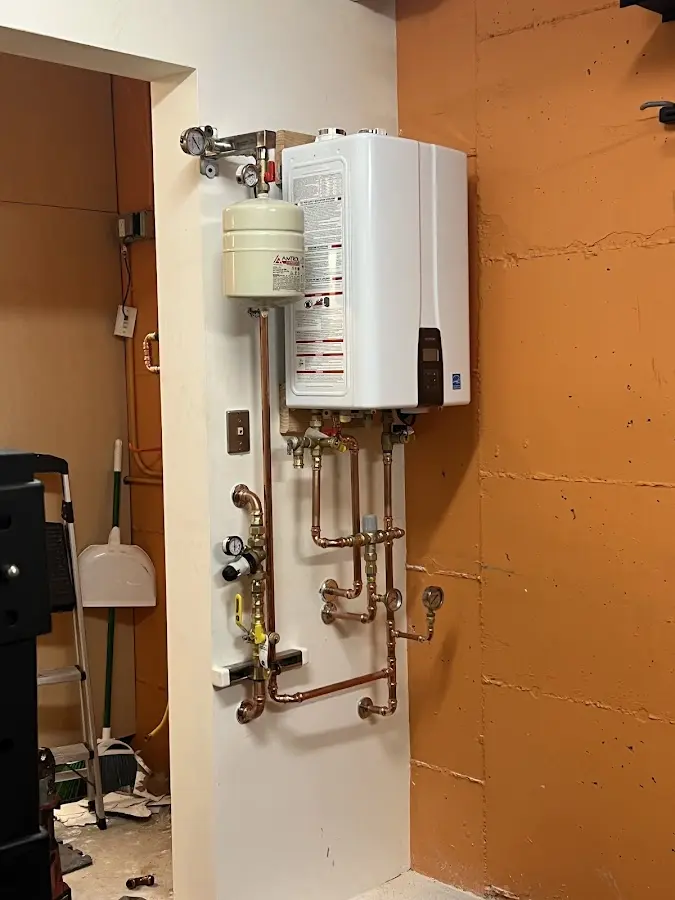 Plumbing technician inspecting water heater connections in Bath